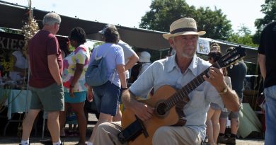 A man plays a guitar at a farmers' market.