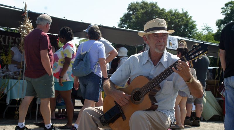 A man plays a guitar at a farmers' market.