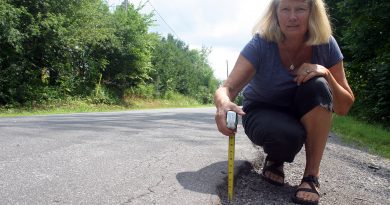 rest Road resident Judy Henry shows off the nearly three-inch curb causing havoc on pedestrians and cyclists on Stonecrest Road. Photo by Jake Davies