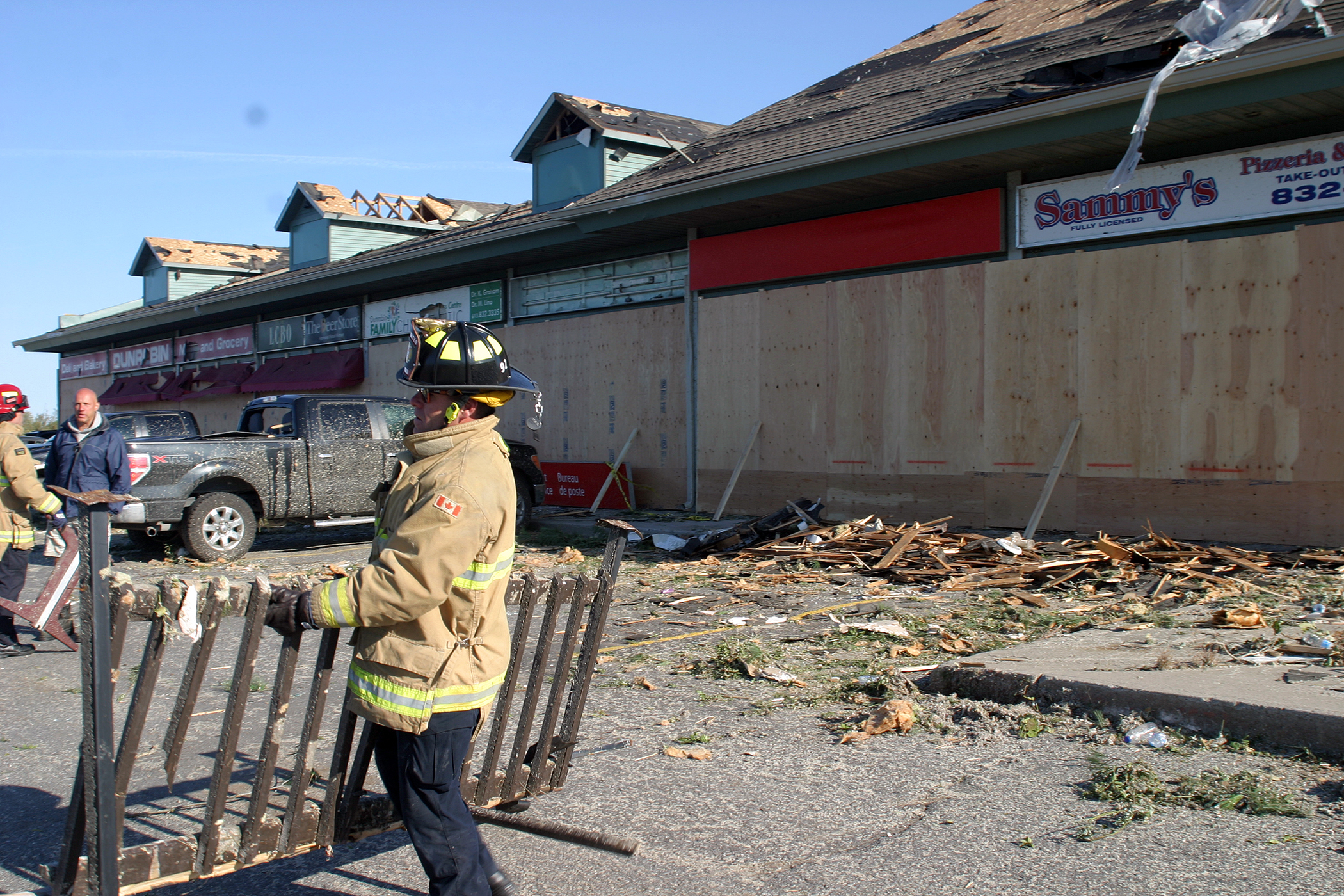 Firefighters, business owners and volunteers clear debris from the mini-mall in Dunrobin. Photo by Jake Davies