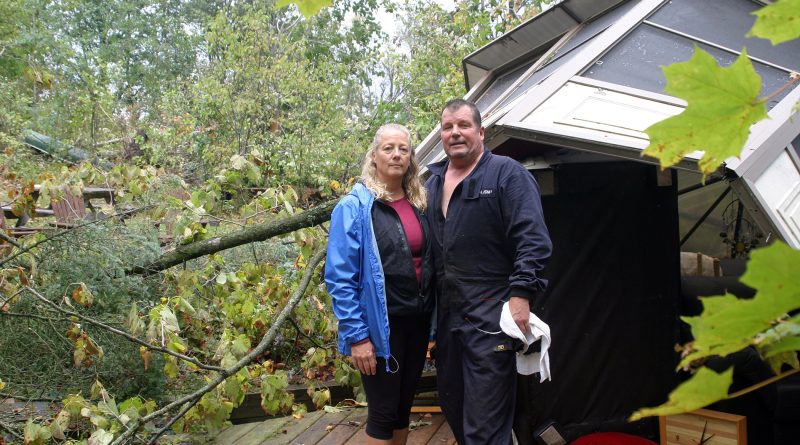 Heather and Allan Gallagher pose by their toppled gazebo. They have spent the last five days cleaning up from last Friday's tornado. Photo by Jake Davies