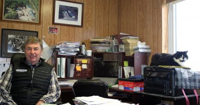 Kinburn Farm Supplies Inc. owner John Herrick sits in his office. Above his right should is the original owner and his team in a photo that dates back to the 1930s. Photo by Jake Davies
