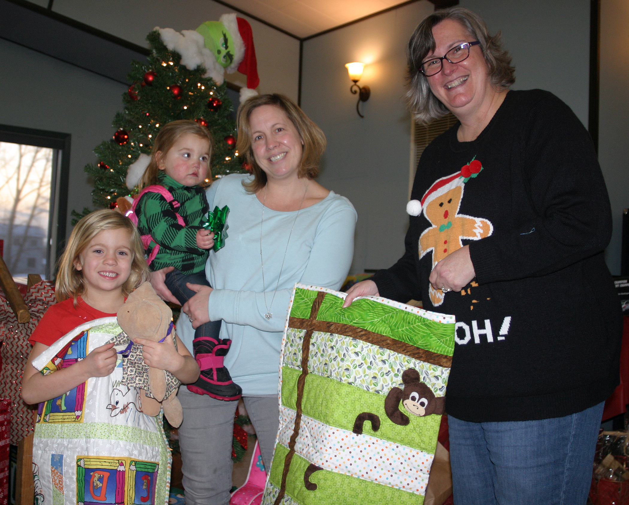 Each child at the party received a handmade quilt as part of their gift bag. From left are Brynn, 5, Jovie, 1, and Rhonda Convery with Kanata Quilt Guild President Brigid Whitnall. Photo by Jake Davies