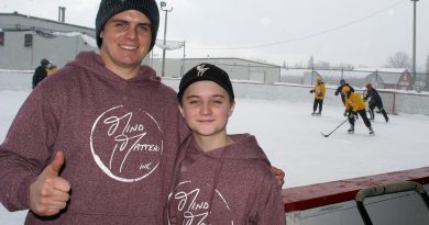 From left, Alex and brother Kaelan Carlson pose for a photo last year while the Hockey4Humanity tournament rages in the background. Photo by Jake Davies