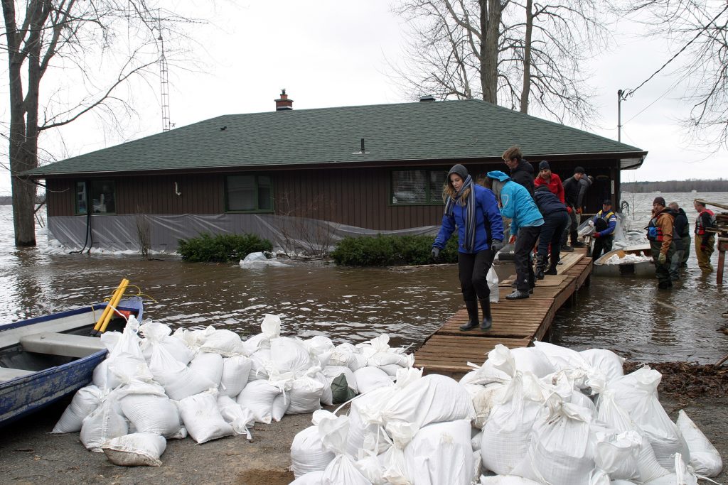 Willola Beach residents form a chain over a small bridge to continue sandbagging a home already surrounded by water. Photo by Jake Davies