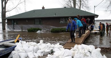 Residents in Willola Beach work on their sandbag wall despite their home being surrounded by water last week. Photo by Jake Davies