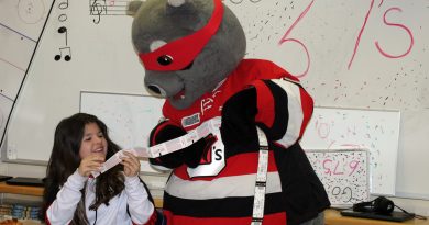 Grade 5/6 student Savannah Swire gets a couple of 67's playoff tickets from Riley the Racoon. Photo by Jake Davies
