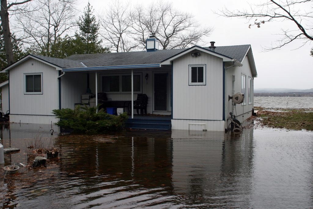 One of the Bayview Drive houses now surrounded by water while three-foot Ottawa River waves crash on the shore behind it. Photo by Jake Davies﻿