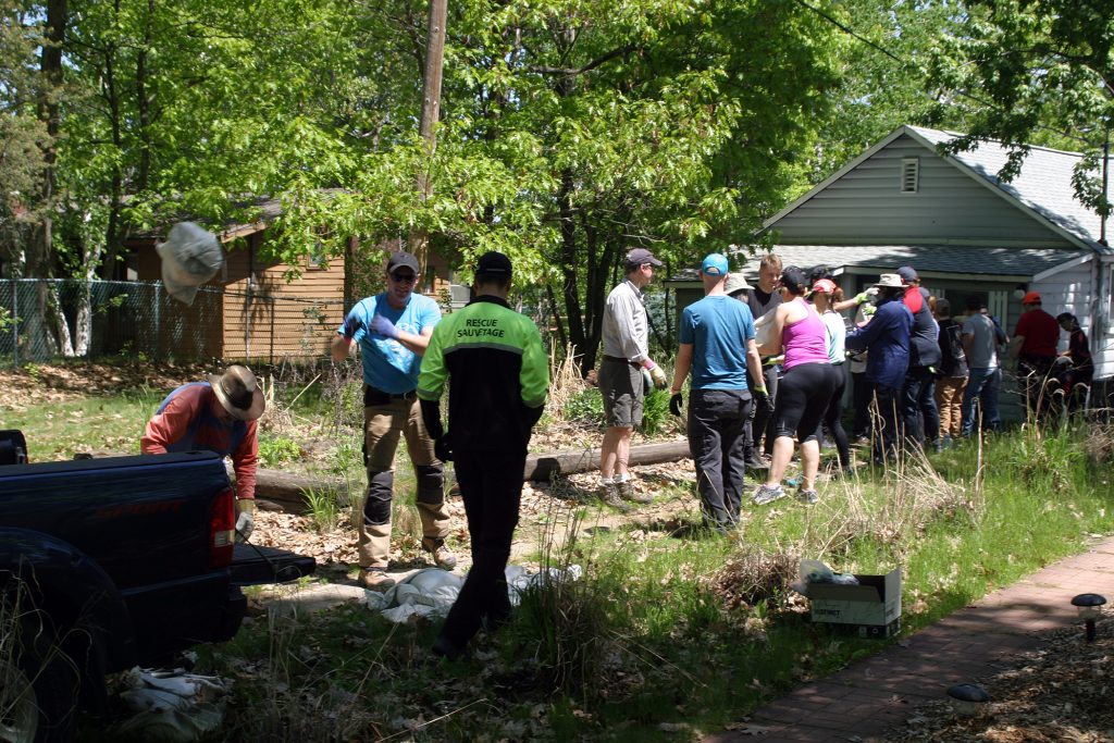 Volunteers form a chain to help remove sandbags from a Bayview Drive home on Saturday. Photo by Jake Davies