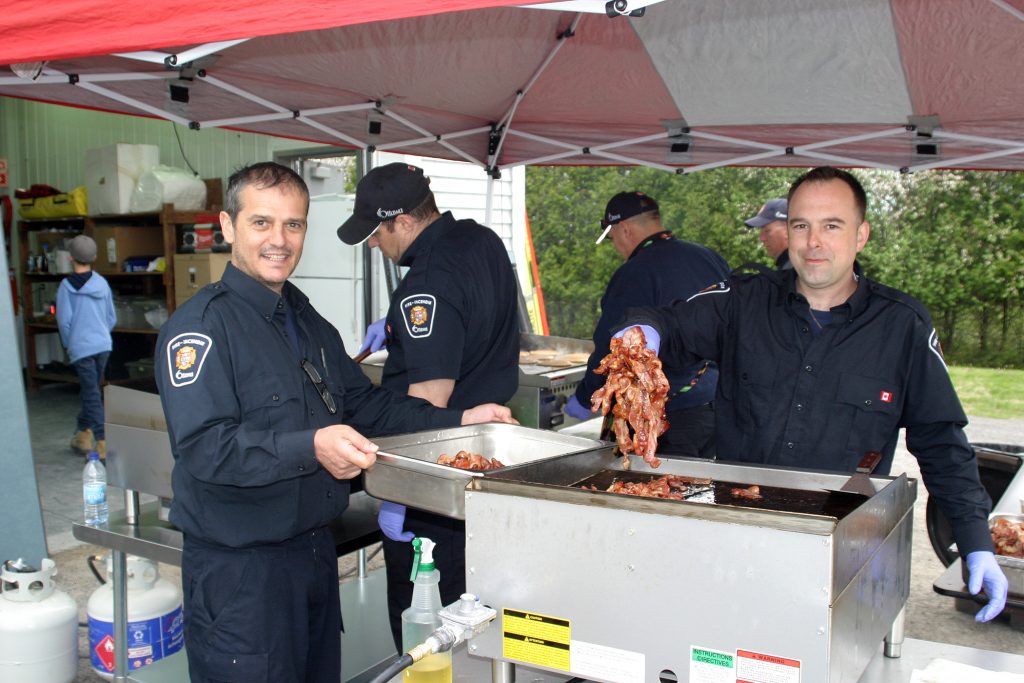 Corkery firefighters, from left, Lorenzo Colaneri and Josh Nunn serve up the bacon while firefighter Steve Logan and Lt. Andrew Good flip some pancakes. Photo by Jake Davies﻿