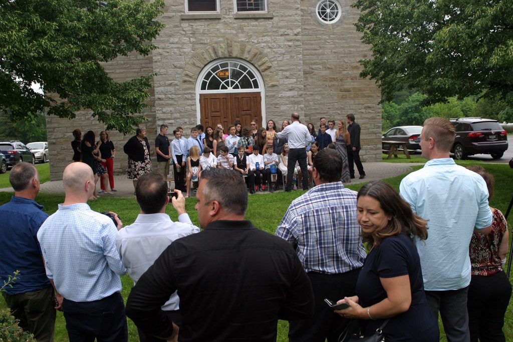 The parent paparazzi scramble for position while the official photographer struggles to organize student (West Carleton Online knows the struggle is real). Photo by Jake Davies