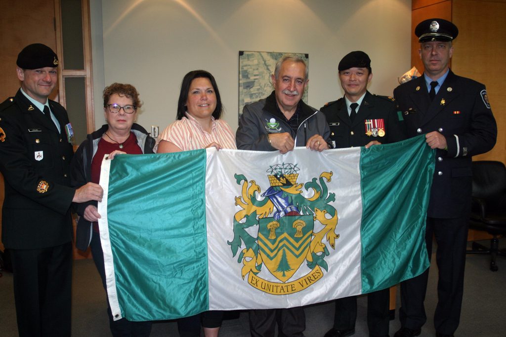 From left, Master Warrant Officer Chris LeBlanc, WCDR's Angela Bernhardt, WCDR's Shannon Todd, Coun. Eli El-Chantiry, Major Kevin Wong and firefighter Paul Asmis pose with West Carleton's township flag. Photo by Jake Davies