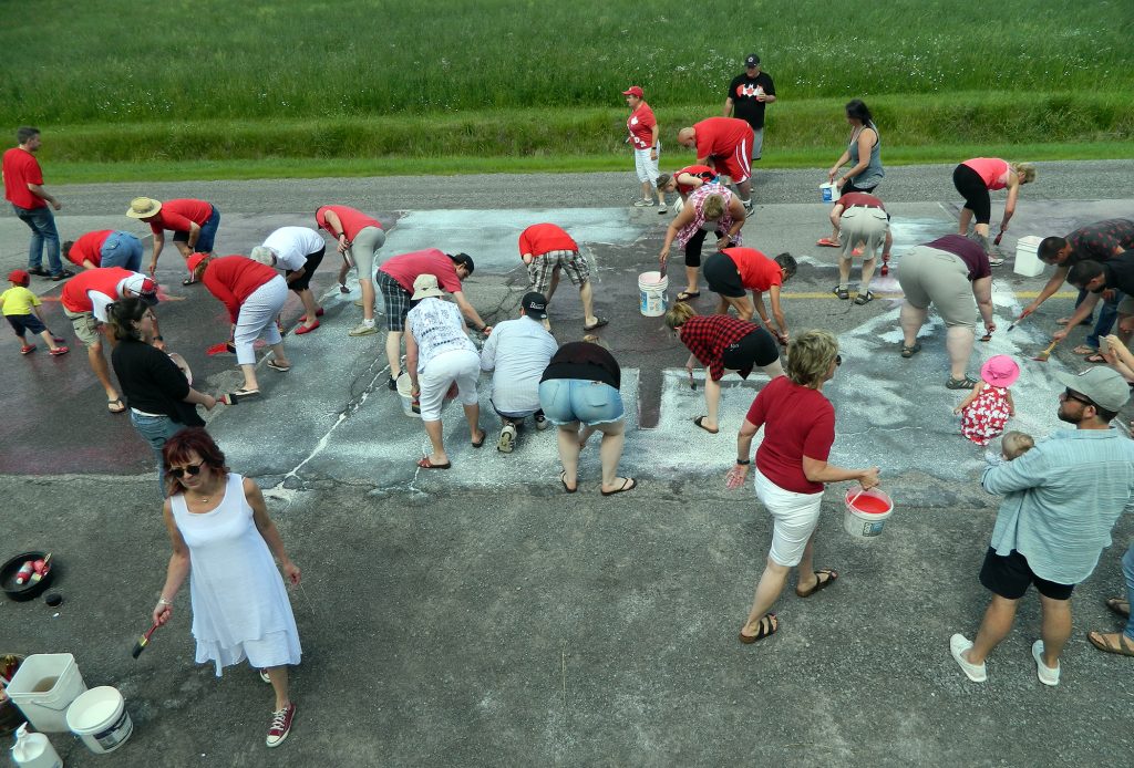 The Borgs' annual Canada Party involves a little work too as party-goers start painting a giant Canada Day Flag that mororists will see on Carp Road fore the next little while. Courtesy Ken Borg