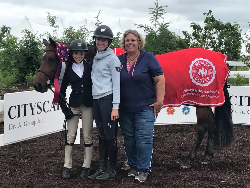 Anna Landry with her coaches Christine Wiggins, Becky Nuth, her pony Lunar Eclipse and those cool, red Weslt Clover championship coolers. Courtesy Karen Landry