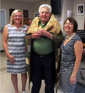 Dr. Roly Armitage poses with his new quilt along with Quilts of Honour Reps Nancy Arbogast and Jill Greenwood. Courtesy Branch 616