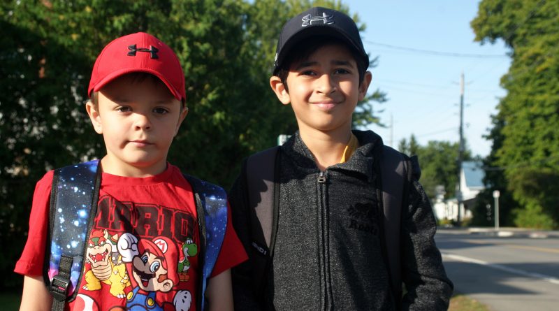 Kinburn's Pearce, 7, and Arjun, 7, are excited to reunite with their school chums as they wait for the bus on the first day of school today. Photo by Jake Davies