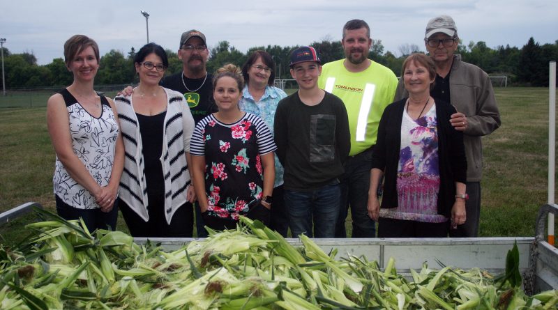 Kinburn Community Association members and volunteers pose in front of 35 dozen corn husks at last Friday's annual Kinburn Corn Roast. Photo by Jake Davies