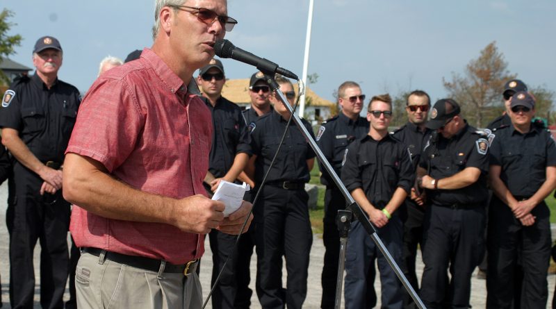 Dunrobin Community Association President and West Carleton Disaster Relief co-chair Greg Patacairk addresses the community in front of volunteer firefighters who were first on scene at Saturday's one year anniversary of the 2018 tornado. Photo by Jake Davies
