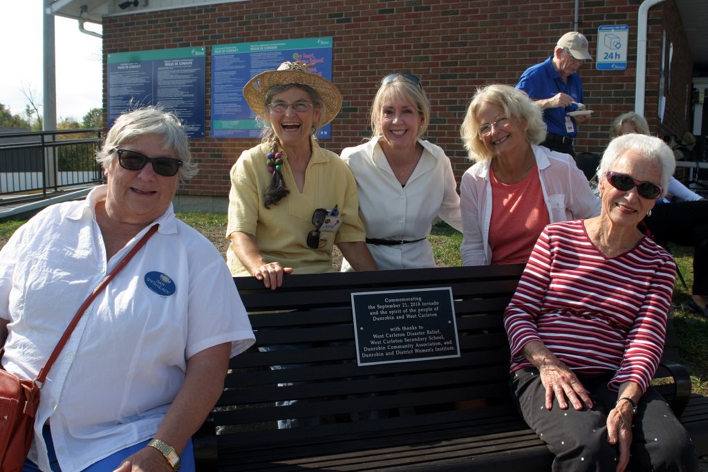 The Dunrobin Women's Institute with MPP Merrilee Fullerton pose with the bench they commisioned for the anniversary. Photo by Jake Davies