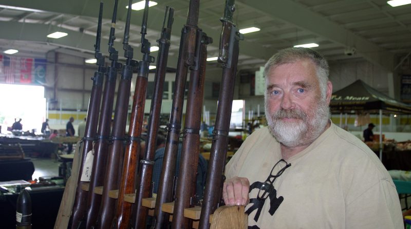 Valley gun show vendor Bill Neslon poses with his collection of World War I and World War II weaponry. Photo by Jake Davies