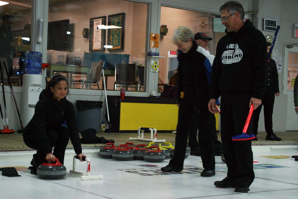 Carp resident Louise Briere gives curling a try as Huntley Curling Club volunteer members share some tips. Photo by Jake Davies