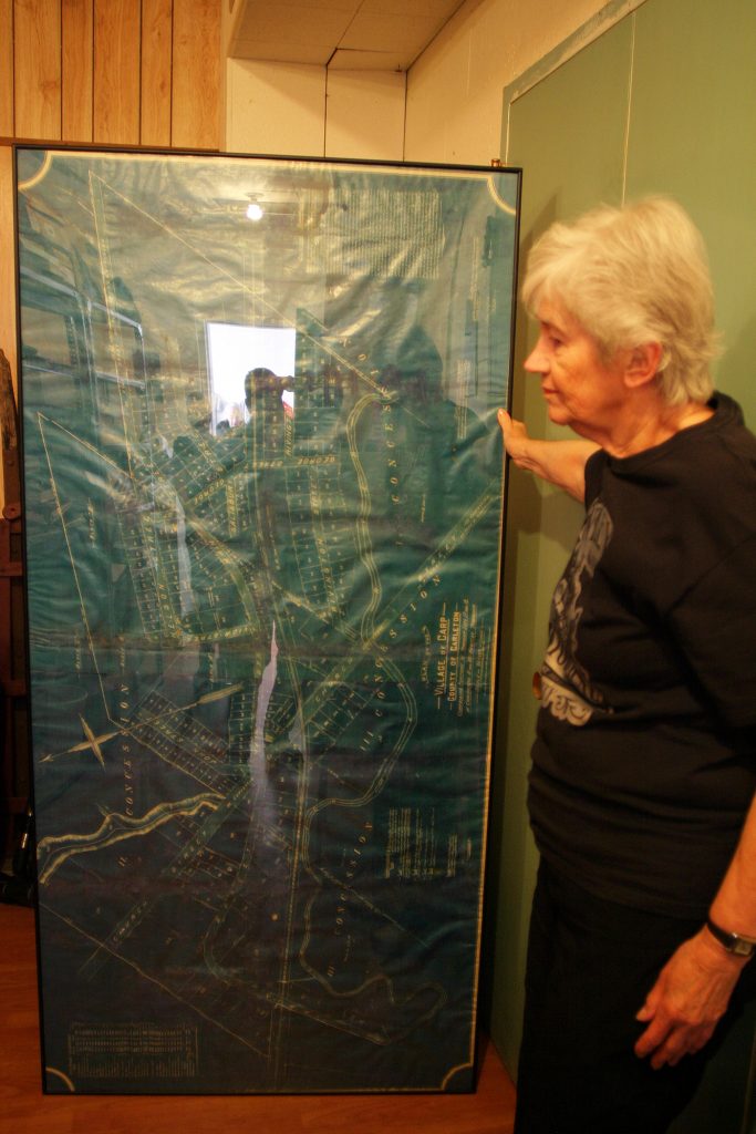 The HHS's Joan Caldwell stands beside a development map of the Village of Carp dating back to 1898. Photo by Jake Davies