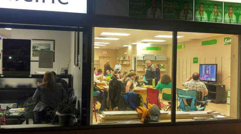 Green Candidate Dr. Jennifer Purdy does a media interview in her clinic (left) while supporters watch the election unfold in next door's campaign headquarters last night. Photo by Jake Davies