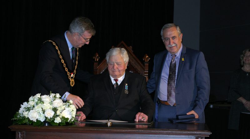 Dr. Roly Armitage signs the induction paper as he is officially sworn in to the Order of Ottawa by Mayor Jim Watson and Coun. Eli El-Chantiry. Photo by Jake Davies