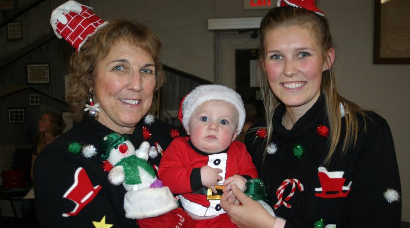 This threesome was awarded best Christmas sweater at last Thursday's cookie exchange in Galetta. From left are grandma Barb Cavanagh, five-month-old Bennett Gwalchmai and mom Cassandra Cavanagh. Photo by Jake Davies