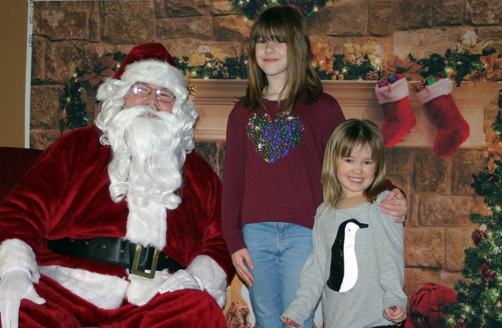 Braelyn, 8, and Piper, 3, pose with Santa at Kinburn's Breakfast with Santa. Photo by Jake Davies