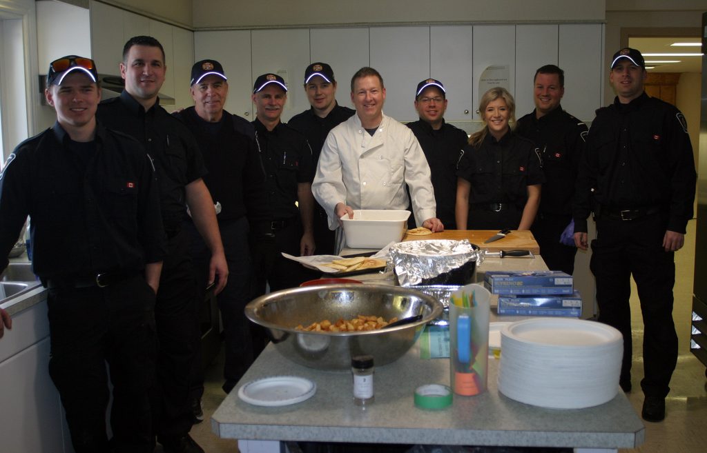 Firefighters from Station 61, with Capt. Luc Chauvin in chef gear, pose for a photo in the kitchen. Photo by Jake Davies
