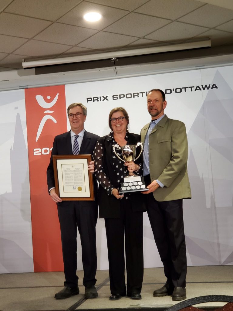 Mayor Jim Watson presents LA and Bevin Schmidt with the Mayor's Cup for their long-time dedication to amateur sports in Ottawa. Courtesy Maha El-Chantiry