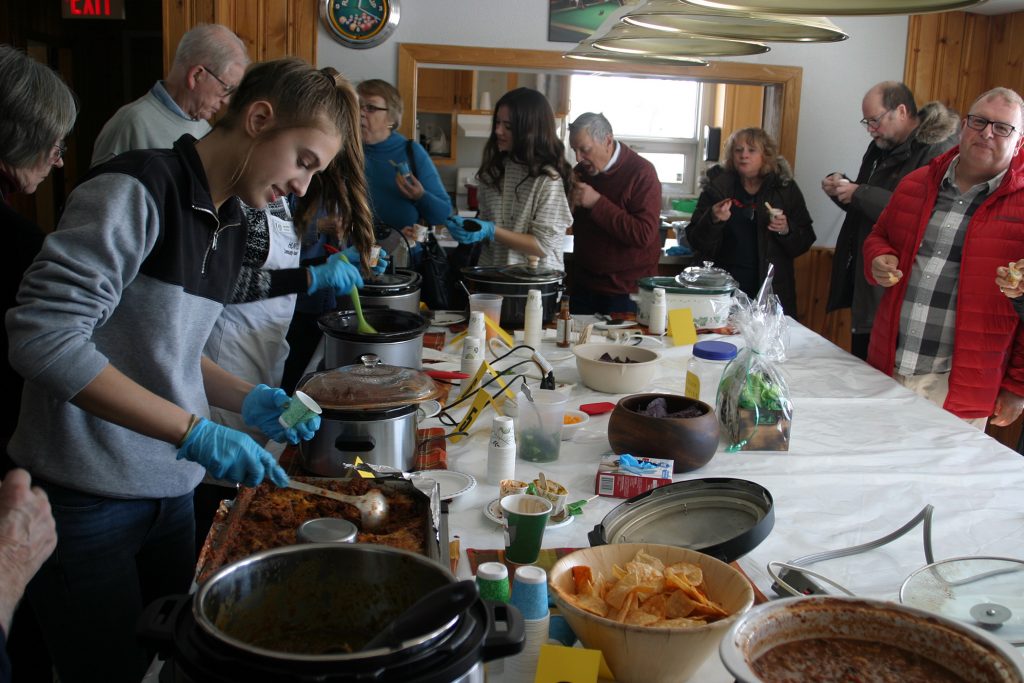 Volunteer Shanna Deugo, far left, helps serve hungry judges a sample of chili. Photo by Jake Davies