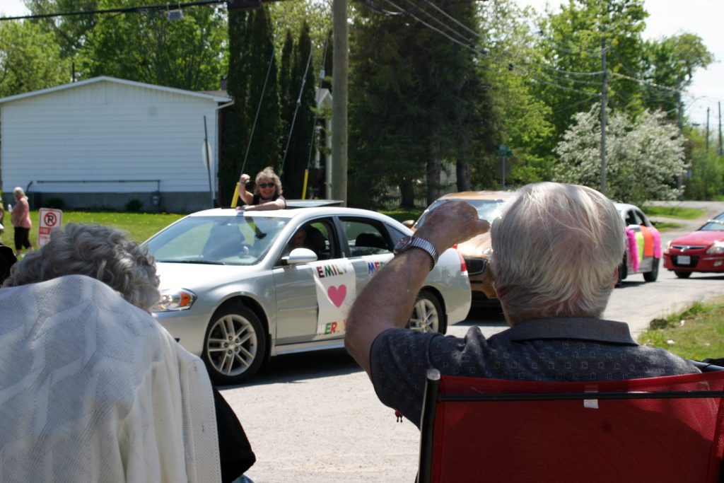 Mervyn and Emily exchange waves with a float in their anniversary parade. Photo by Jake Davies