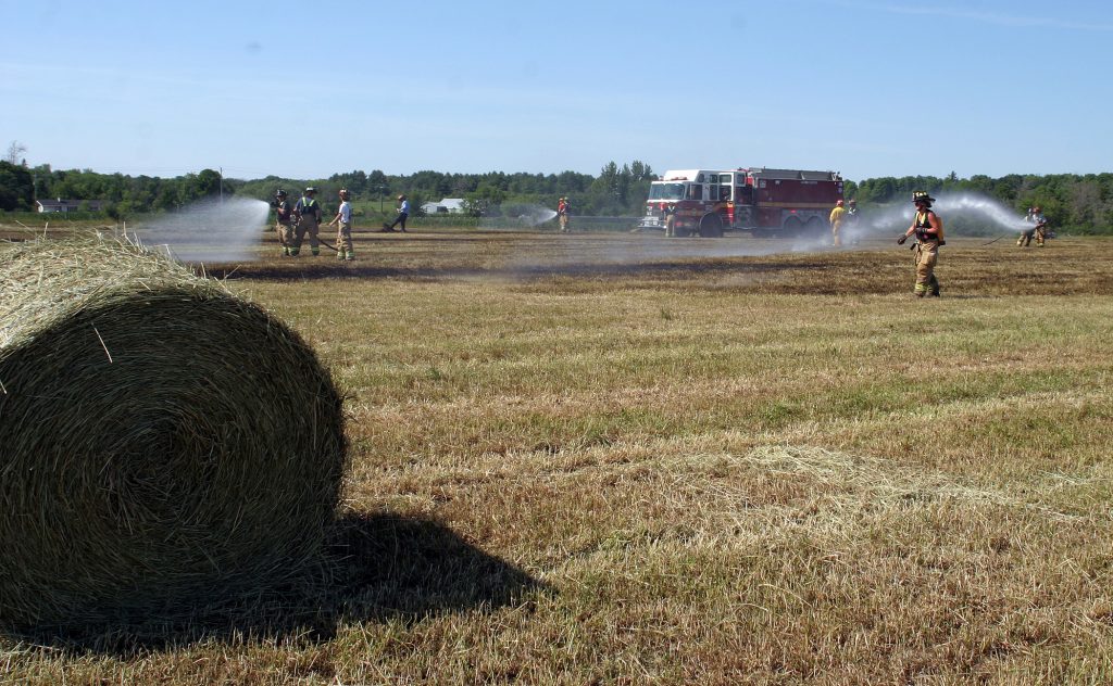 Volunteer firefighters make sure the hay fire is properly doused earlier this afternoon. Photo by Jake Davies