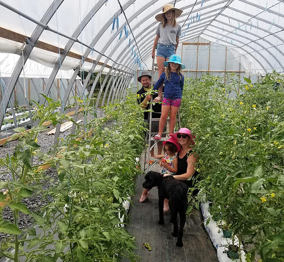 Earl, Amy and their daughters Gabriella, 10, Ariel, 7, and Layla, 3, Spinks at work in the greenhouse. Photo by Karen Foster