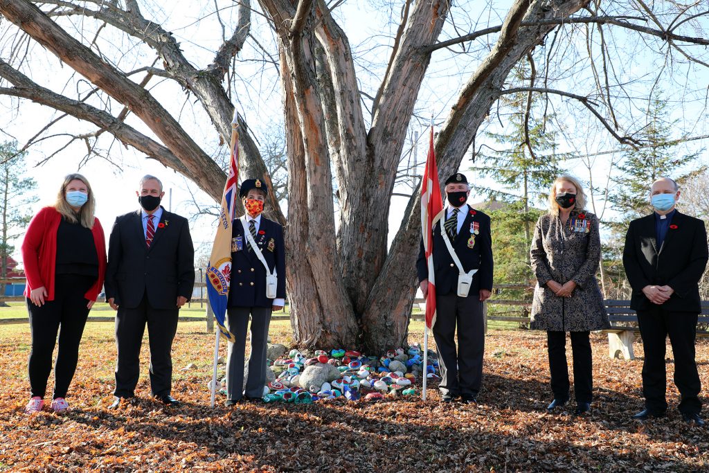 From left, St. Michael's Principal Chantel Couture-Campbell, Coun. Eli El-Chantiry, Colour Guard Arleen Morrow and Rob Gallant, MP Karen McCrimmon and Father John Orban pose in front of a large collection of symbolic Remembrance Day rocks.