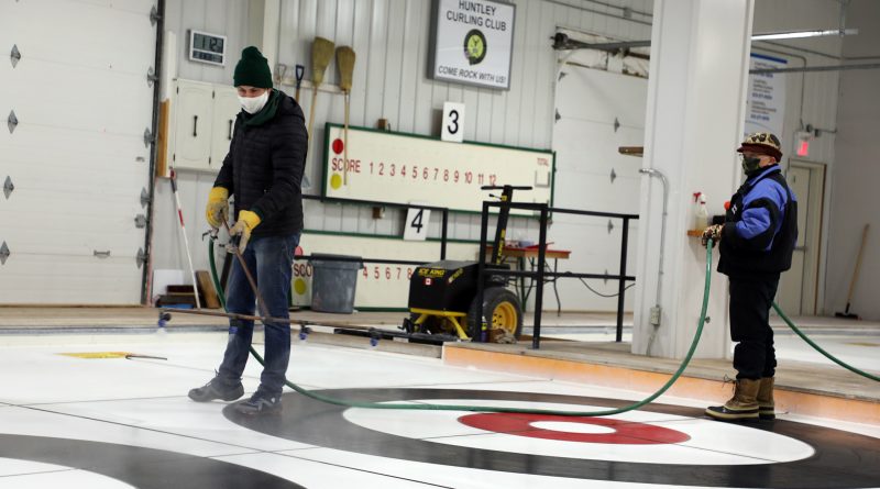 Huntley volunteers work on making curling ice.
