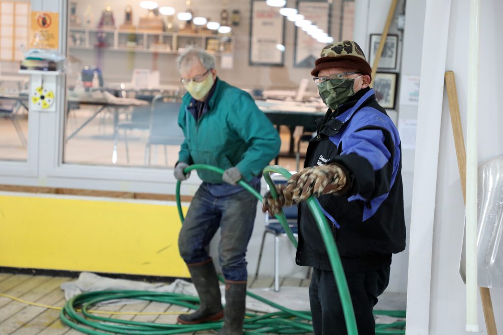 Two volunteers help make ice  at the curling club.