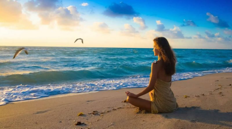 A woman meditates on the beach.