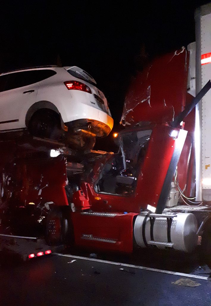 A photo of the car, from the other truck's trailer, damaged the cab of the truck that ran in to it.