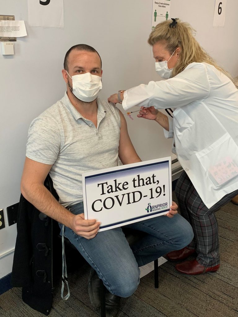 Emergency Department nurse Joshua Paterson gets vaccinated by Cheryl Bourgeau, Occupational Health and Safety. Courtesy ARH