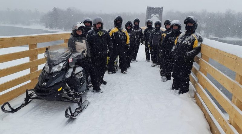 Snowmobilers pose on the world's longest snowmobile bridge.