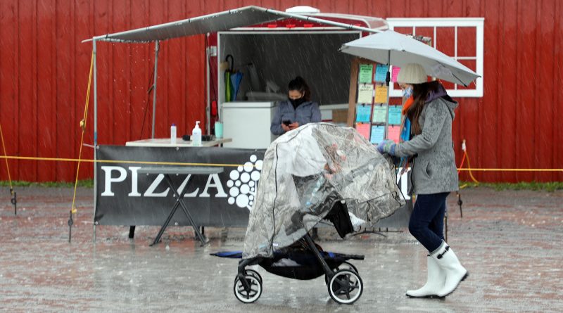 A mom and her baby walk during a rainy day.