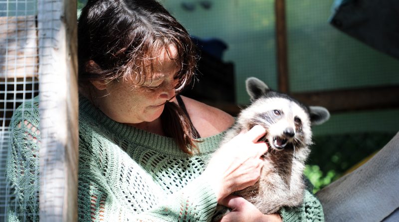 A photo of Lynne Rowe with a racoon.