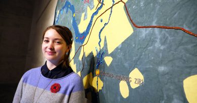 A photo of Algonquin artist Mairi Brascoupé in front of her beaded map.