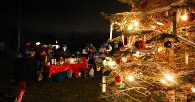 Dunrobin residents sing carols behind a Christmas tree.
