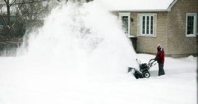 A photo of a man snowblowing.