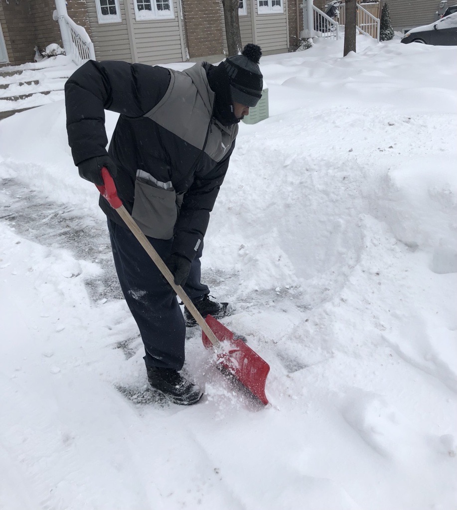 A photo of a man shovelling snow.