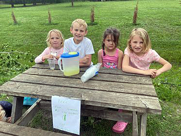 A photo of four kids and lemonade.